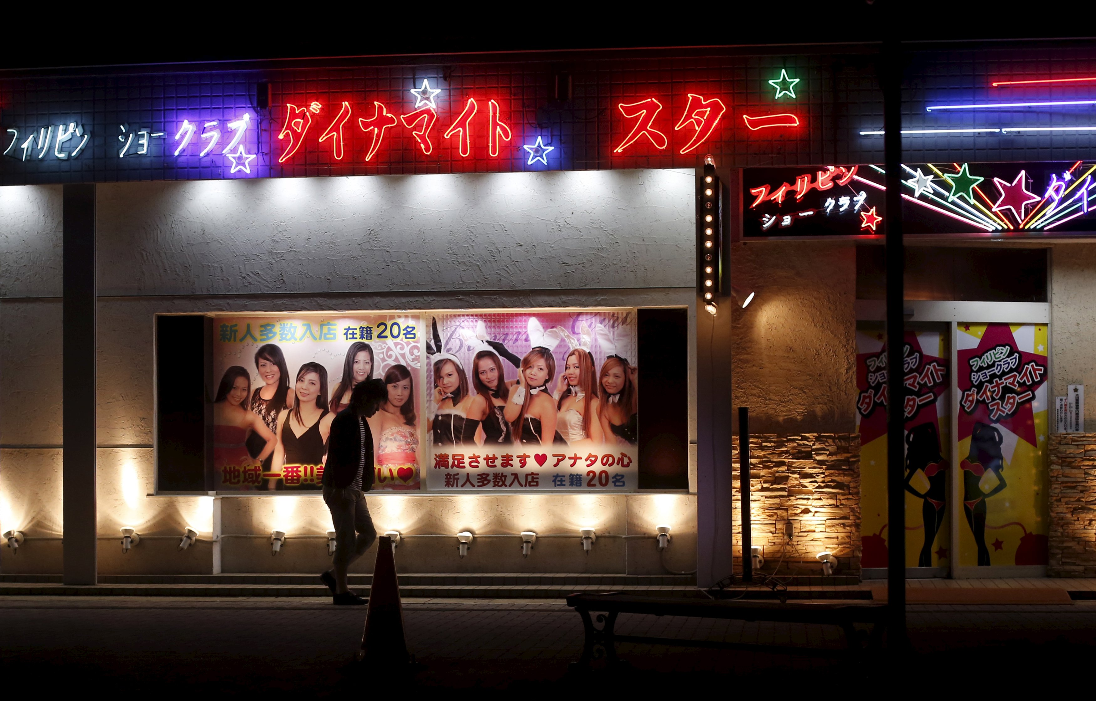 A man walks outside a club with an advertisement depicting women from the Philippines in the red light district in Ota, Gunma prefecture, north of Tokyo, Japan, April 24, 2015. Picture taken April 24, 2015. To match Special Report JAPAN-SUBARU/ REUTERS/Yuya Shino
