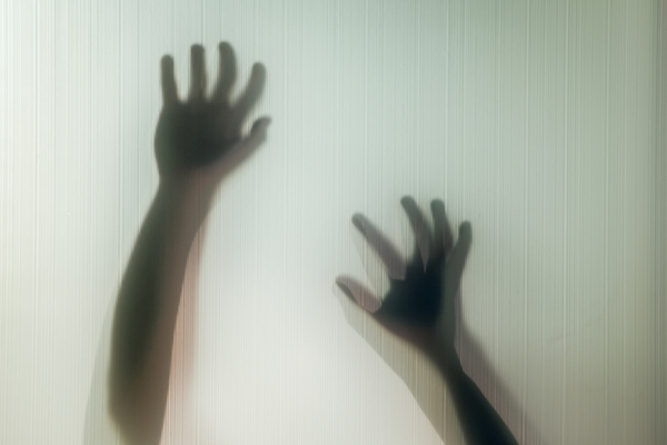 Halloween hands behind transparent glass background as silhouette